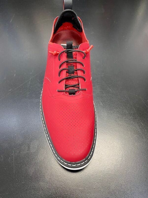 A pair of red shoes with black laces on a black surface.