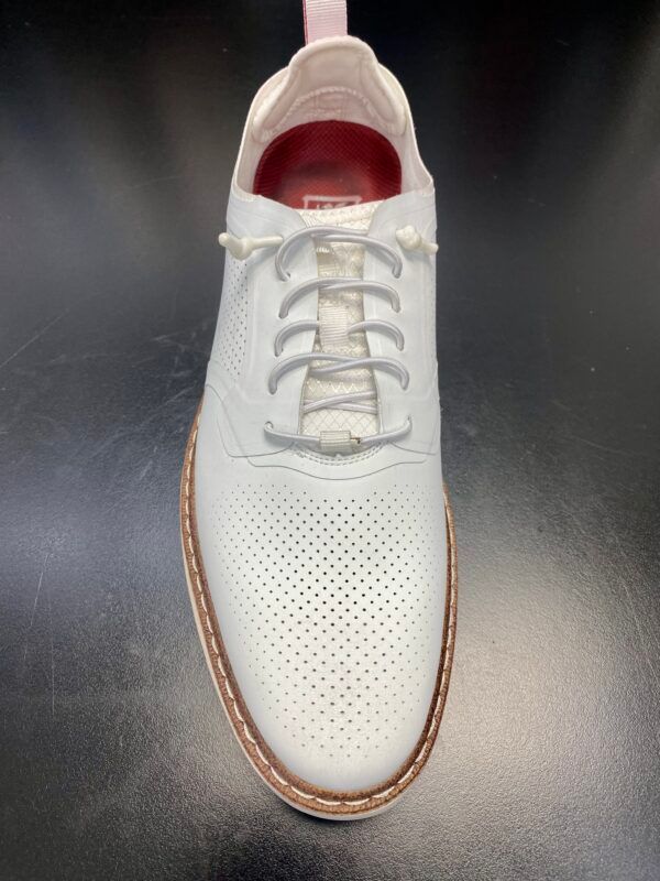 A pair of white shoes with white laces on a black surface.