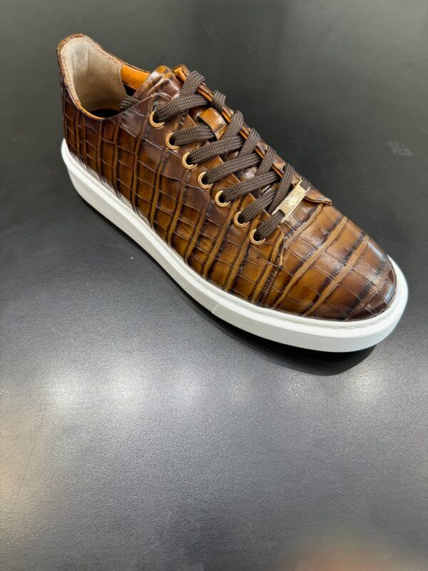 A pair of brown sneakers with a white sole on a black surface.
