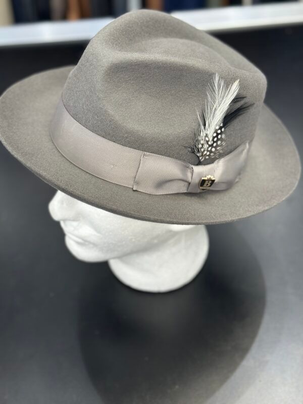 A grey fedora hat with a feather on it is on a mannequin head.