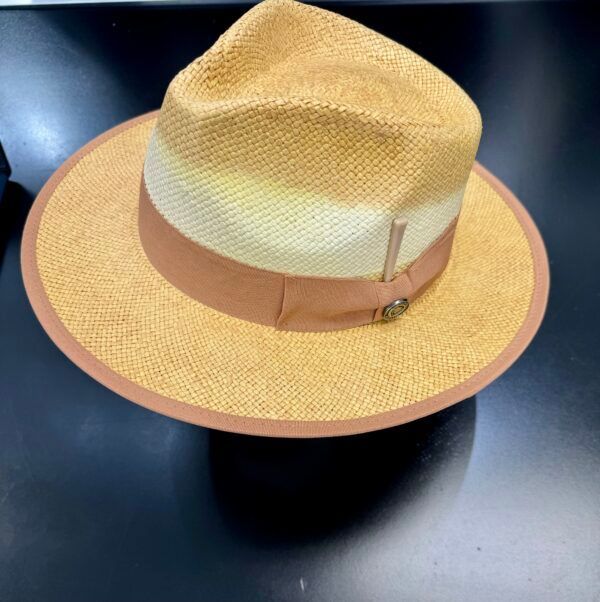 A straw fedora hat with a brown band sits on a table