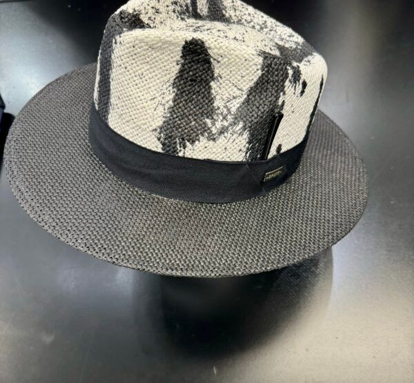 A black and white hat with a black band is sitting on a table.