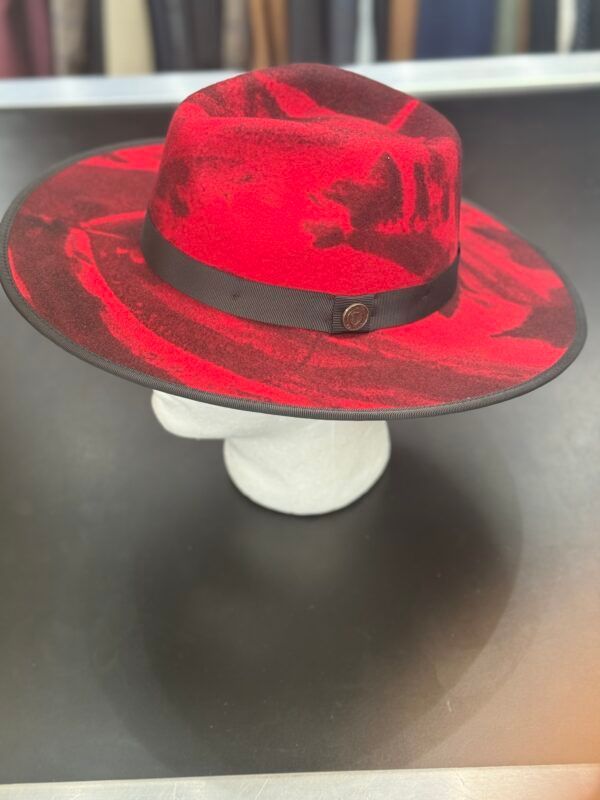 A red and black hat is sitting on top of a white mannequin head.