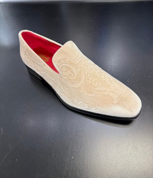 A pair of tan shoes with a red lining on a black surface