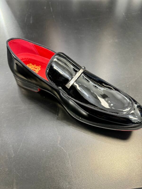 A pair of black loafers with a red lining on a table.