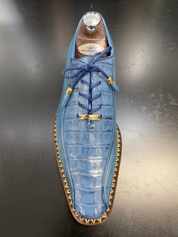 A pair of blue shoes with blue laces are sitting on a black table.