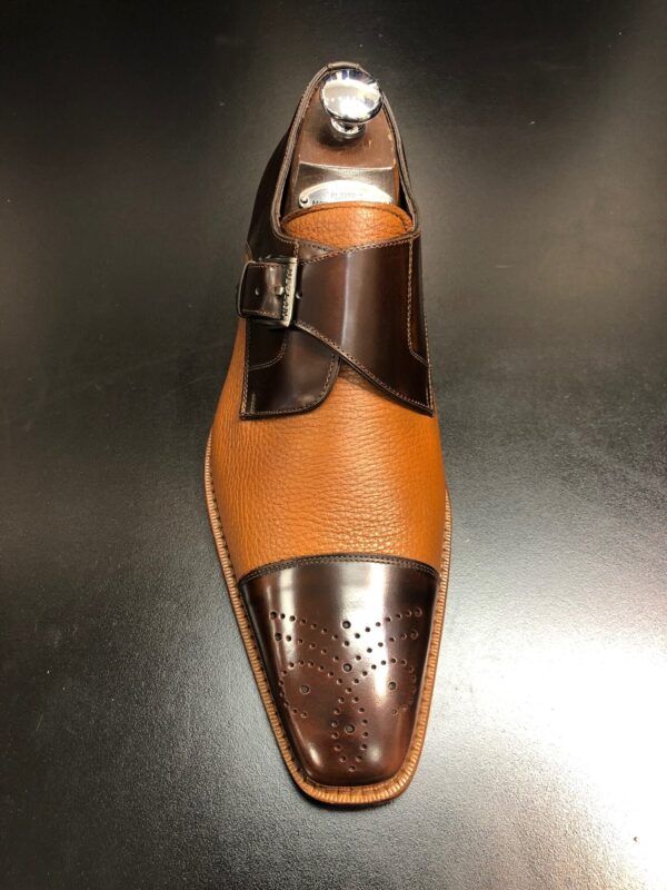 A brown and black shoe is sitting on a black surface.
