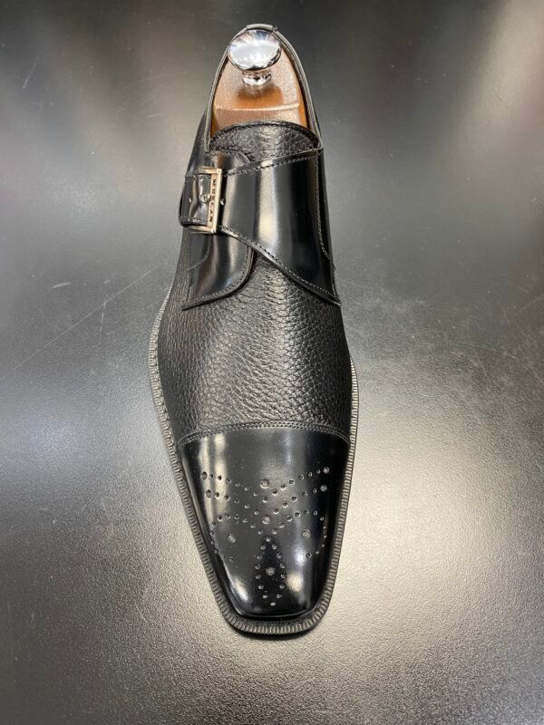 A pair of black monk strap shoes are sitting on a black surface.
