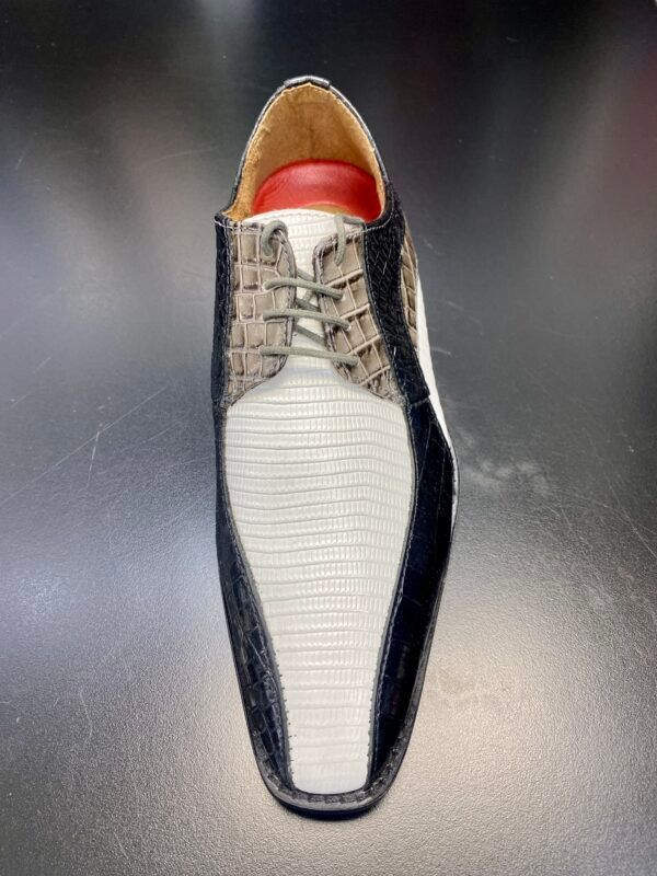 A pair of black and white shoes with a red sole on a black surface.
