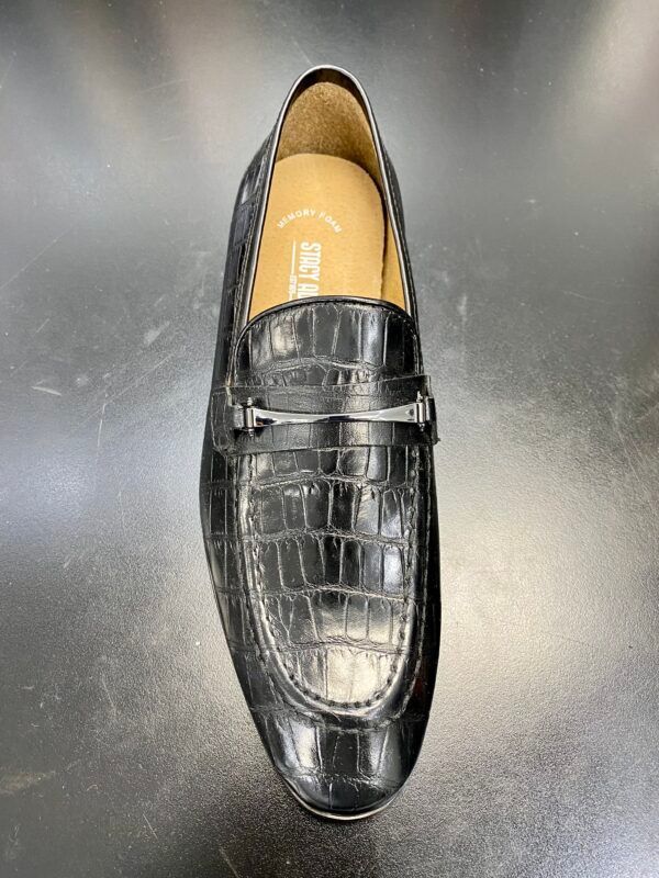 A pair of black loafers sitting on top of a black table.