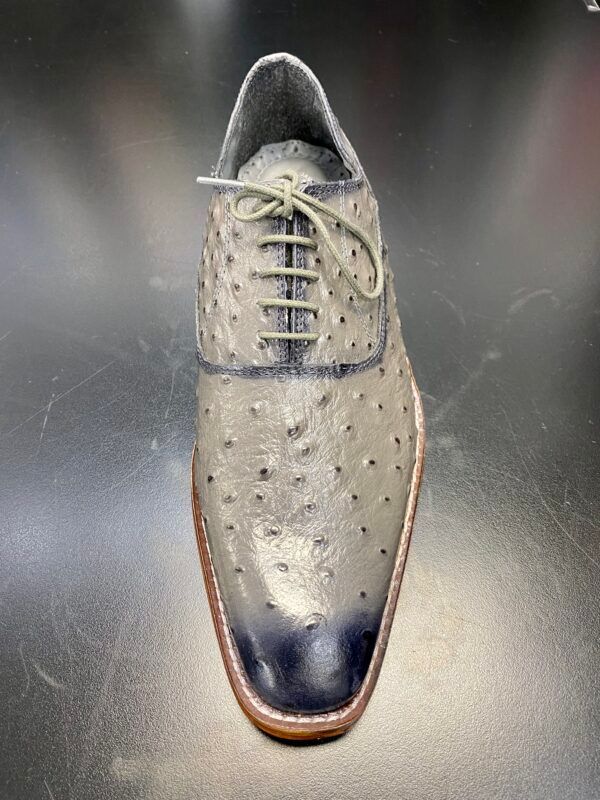 A pair of ostrich leather shoes are sitting on a black table.