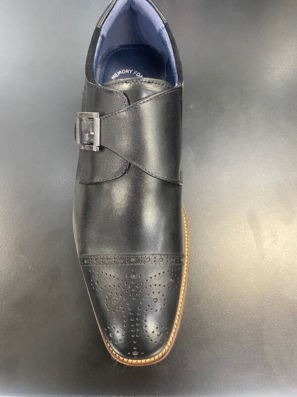 A pair of black shoes with a buckle on the side are sitting on a table.