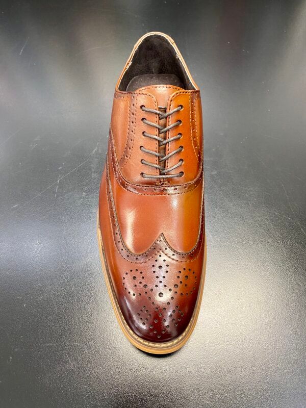 A close up of a pair of brown shoes on a black surface.