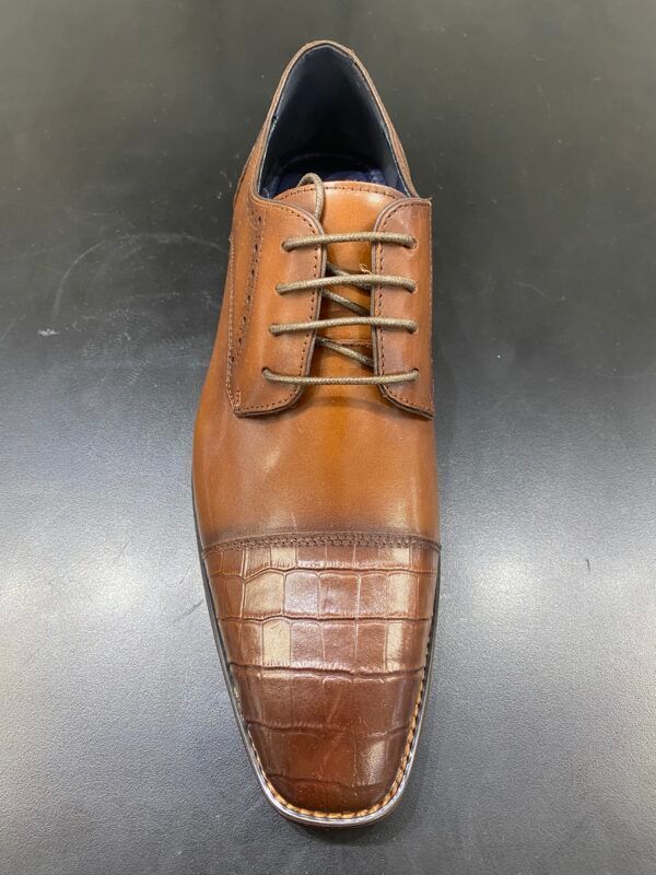 A pair of brown leather shoes with laces on a black surface.