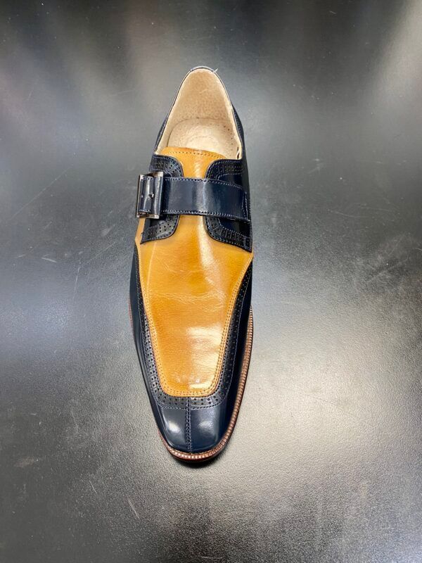 A pair of black and yellow shoes with a buckle on a black surface.