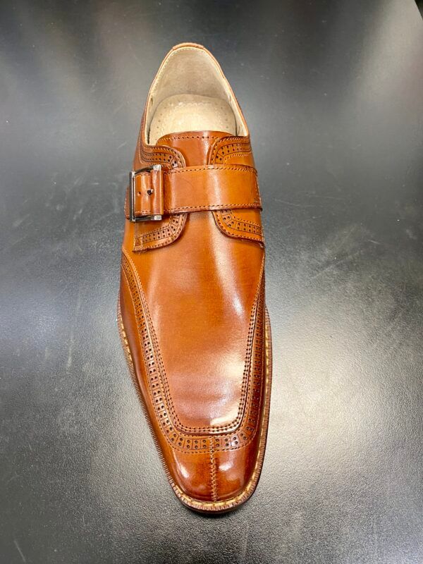 A pair of brown leather shoes with a buckle on a black surface.