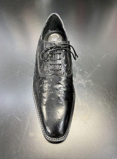 A pair of black shoes with laces on a black surface.