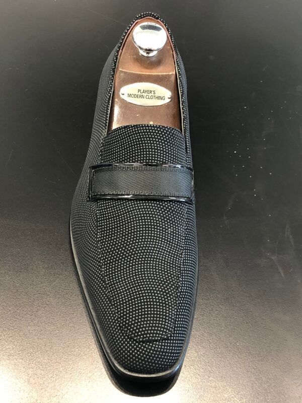 A pair of black loafers sitting on top of a black table.