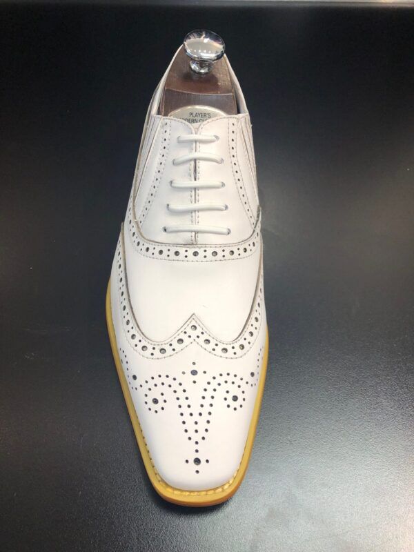 A pair of white shoes with yellow soles on a black surface