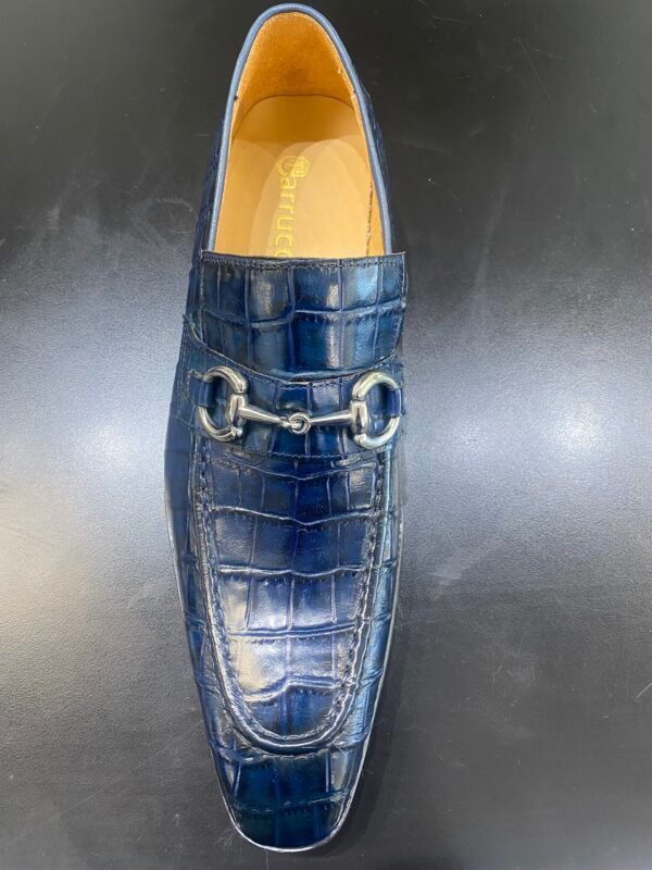 A pair of blue shoes with a horse bit on a black surface.