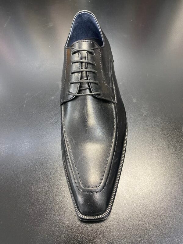 A pair of black leather shoes are sitting on top of a black table.