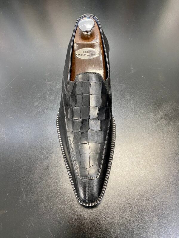 A black shoe is sitting on top of a black table.