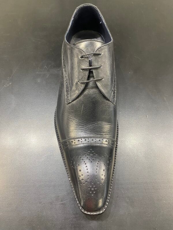 A pair of black men 's shoes are sitting on a black surface.
