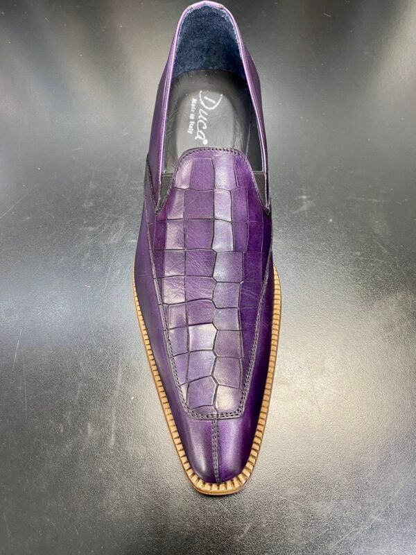 A pair of purple shoes are sitting on a black surface.