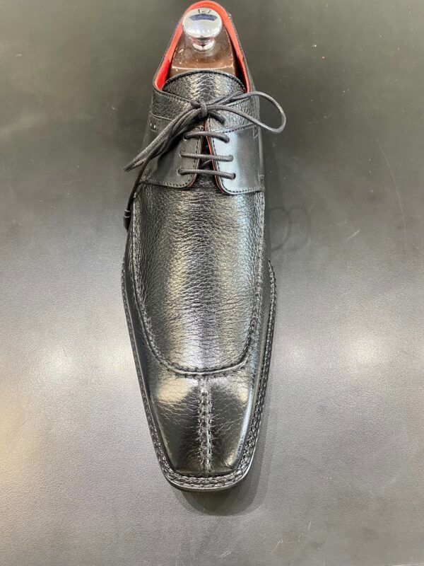 A pair of black shoes with red laces on a black surface.