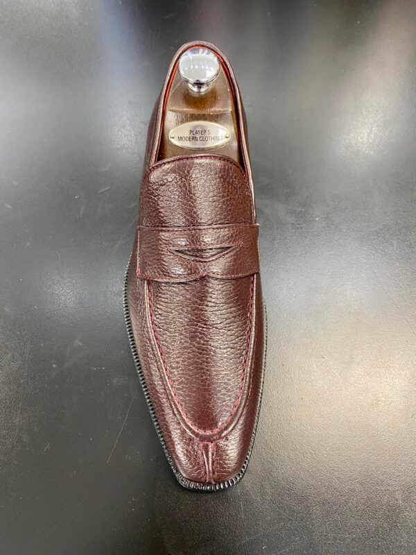 A pair of brown loafers sitting on top of a black table.