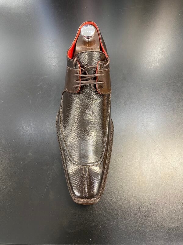 A pair of brown leather shoes with red laces on a black surface.