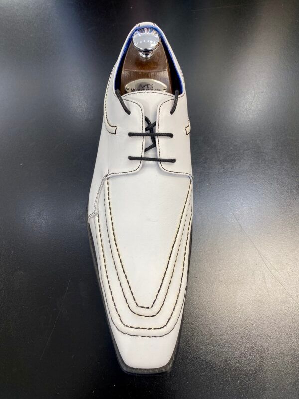 A pair of white shoes with black laces on a black surface.