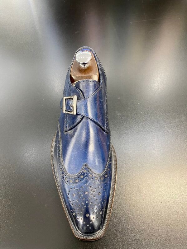 A pair of blue shoes with a buckle on a black surface.