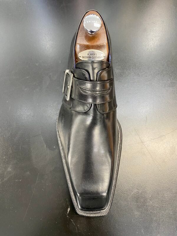 A pair of black leather shoes sitting on top of a black table.
