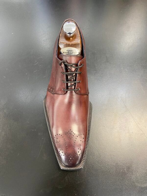 A pair of brown leather shoes sitting on top of a black table.
