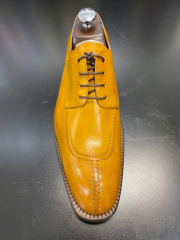 A pair of yellow shoes with black laces on a black surface