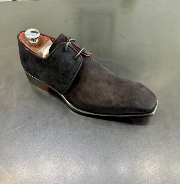 A black shoe with red laces is sitting on a table