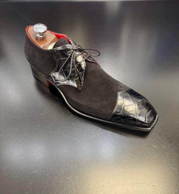 A black shoe is sitting on a black table