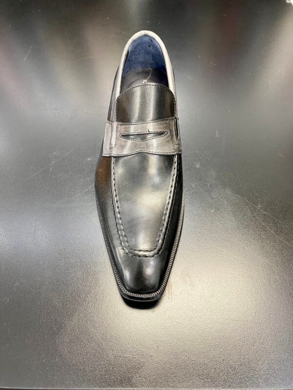 A pair of black loafers sitting on top of a black table.