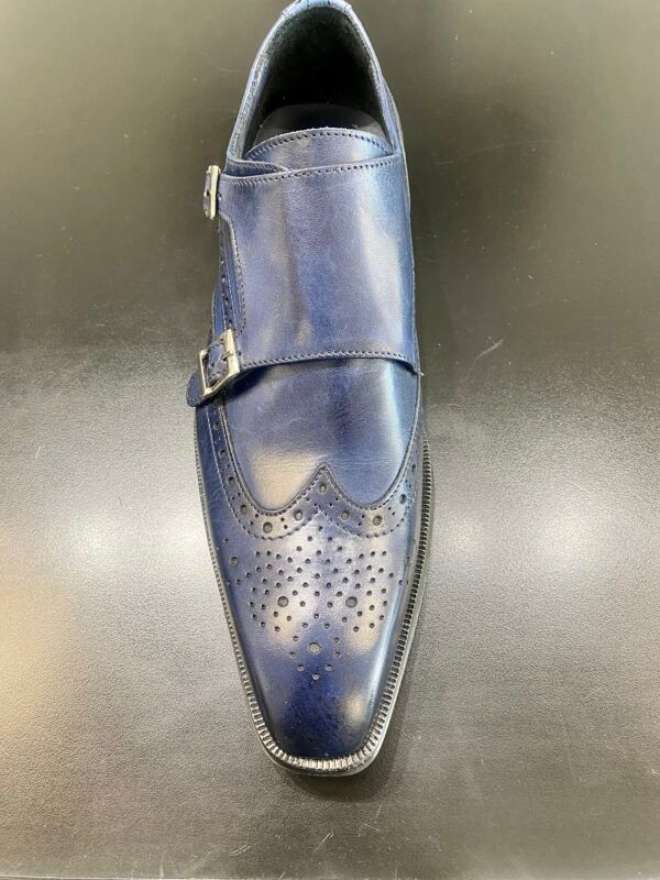 A pair of blue monk strap shoes are sitting on a black surface.