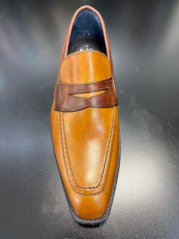 A pair of brown leather loafers are sitting on a black surface.