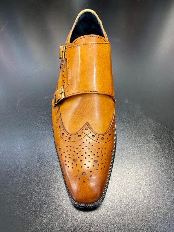 A pair of brown leather monk strap shoes on a black surface.
