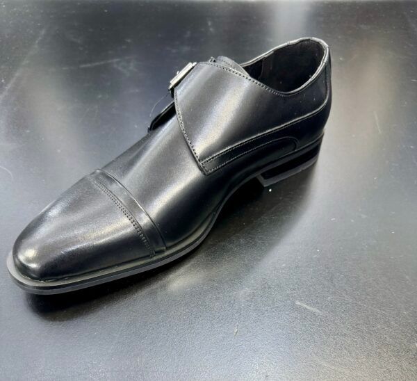 A black shoe is sitting on a black surface