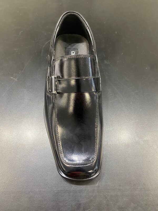 A pair of black shoes are sitting on a black surface.