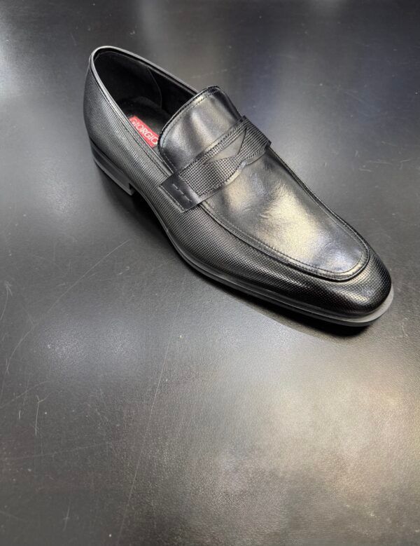 A pair of black leather loafers sitting on top of a black table.