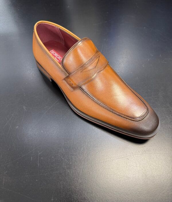 A brown shoe with a brown sole is on a black surface