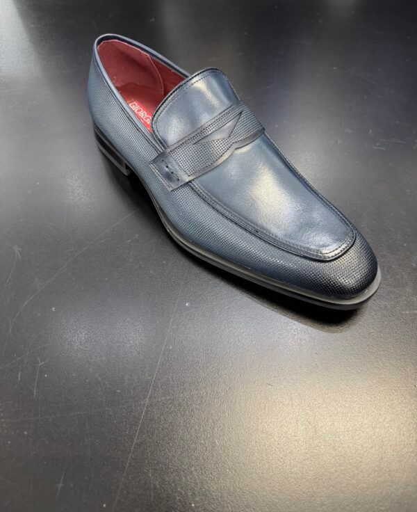 A pair of blue loafers with red soles are sitting on a black surface.