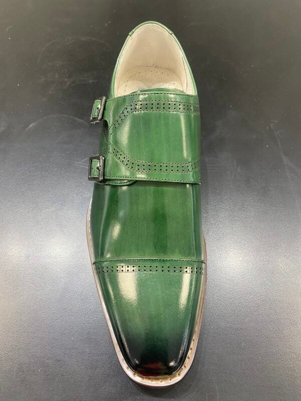 A pair of green double monk strap shoes on a black surface.