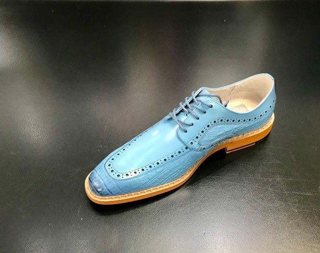 A light blue shoe is sitting on a black surface.