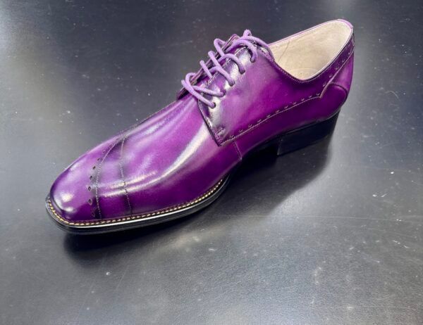 A purple shoe is sitting on a black surface